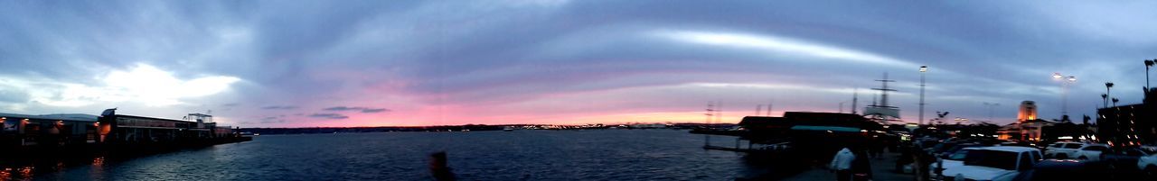 Boats in harbor against cloudy sky