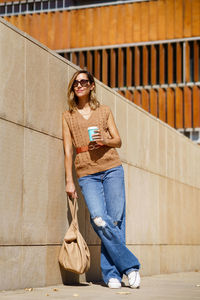 Portrait of young woman sitting against wall