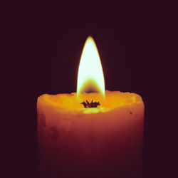 Close-up of lit candle in darkroom