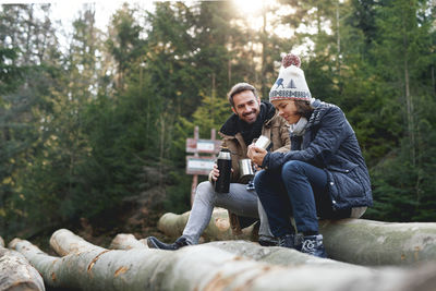 Happy father and daughter having coffee while camping at forest