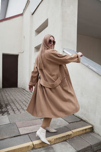 Female fashion model, posing for a full length photo, wearing total beige outfit, street fashion