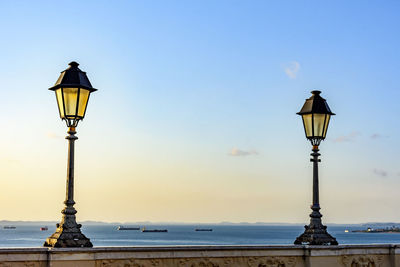 Old lanterns lighting on wall in salvador with the all saints bay in the background at sunset