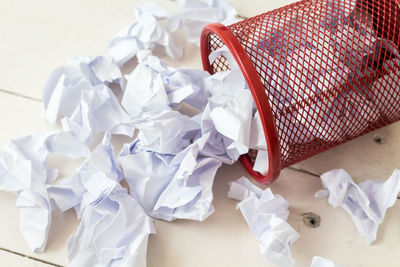 High angle view of crumpled papers by garbage can on floor