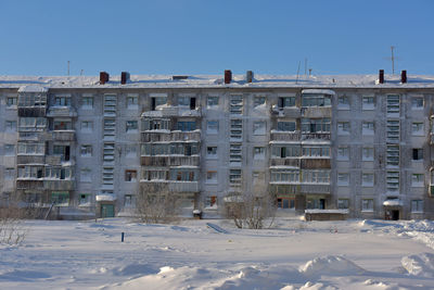 Buildings on snow covered field against sky