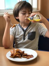 Boy drinking juice from bottle while sitting on chair at restaurant