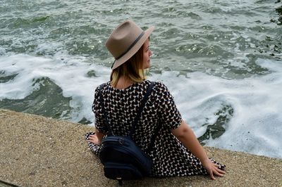 Rear view of young woman with backpack sitting at beach