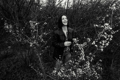 Portrait of woman standing by tree in forest