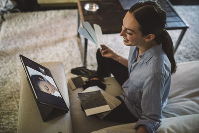 High angle view of smiling female entrepreneur holding fabric swatch while talking to colleague on video conference at h