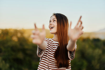 Portrait of young woman standing against sky