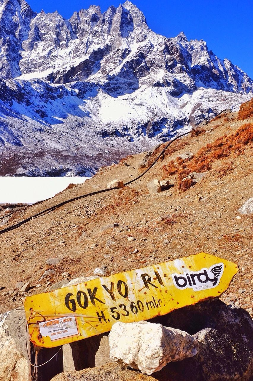 mountain, text, western script, mountain range, communication, rock - object, rock formation, clear sky, landscape, snow, rocky mountains, blue, tranquility, nature, beauty in nature, tranquil scene, scenics, non-urban scene, physical geography, snowcapped mountain