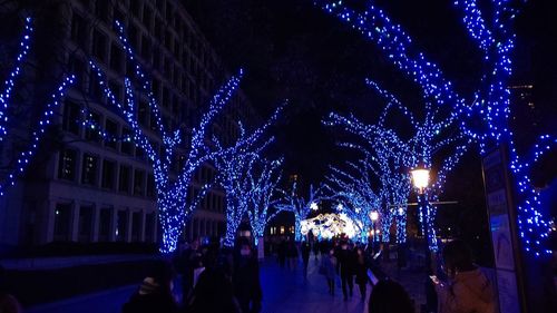 People on illuminated christmas lights at night