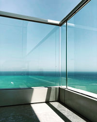 Swimming pool by sea against sky seen through window