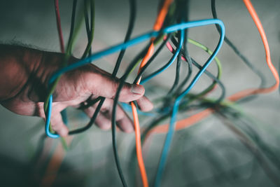 Cropped hand of man amidst colorful wires