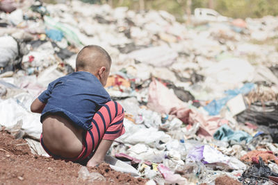 Rear view of boy sitting on garbage