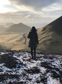 Rear view of man standing on mountain during winter