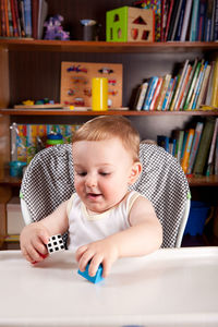 Cute baby boy playing with toy blocks on table