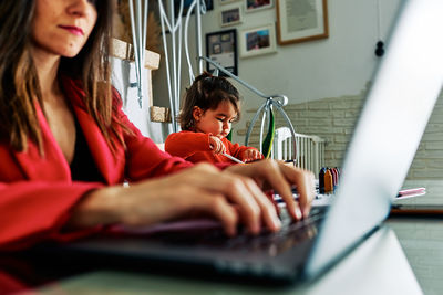 Young executive woman working from home while taking care of her young daughter