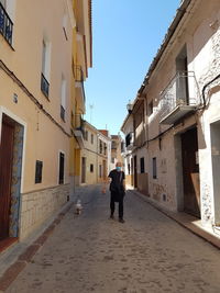 Rear view of people walking on street amidst buildings in city