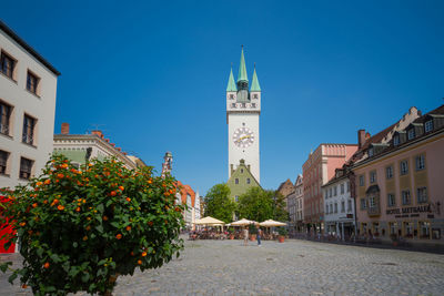 Street amidst buildings in city against clear blue sky