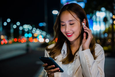 Young woman using mobile phone at night