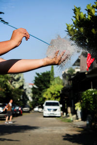 Hand by tree against sky