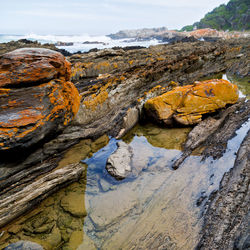 Rock formation on beach against sky