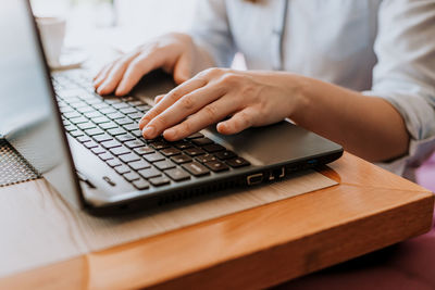 Midsection of person using laptop on table