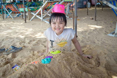 Portrait of smiling girl buried in sand at beach