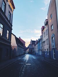 Empty road amidst buildings against sky