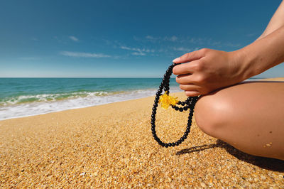 Midsection of person on beach against sky