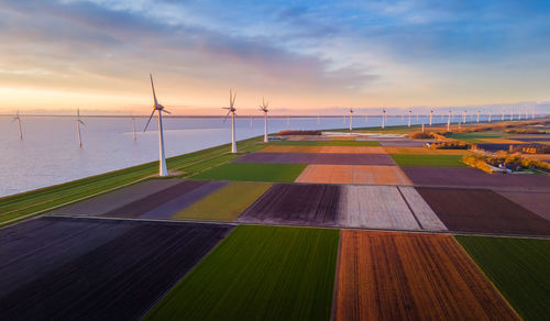 A row of wind turbines seen from above in a field under a cloudy sky