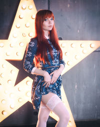 Portrait of seductive woman wearing blue dress standing against illuminated star