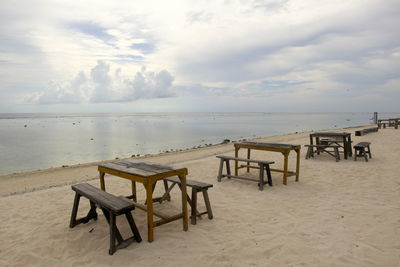 Chairs and table on beach against sky