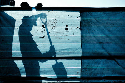 A silhouette of construction worker behind a canvas fence