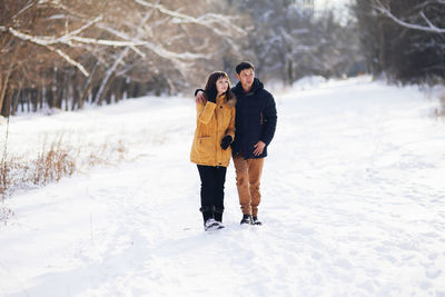 Full length of friends standing on snow