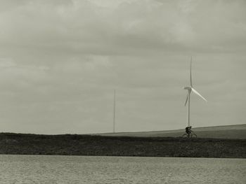 Silhouette of windmill against cloudy sky