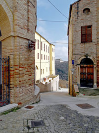 Walkway amidst buildings in town against sky