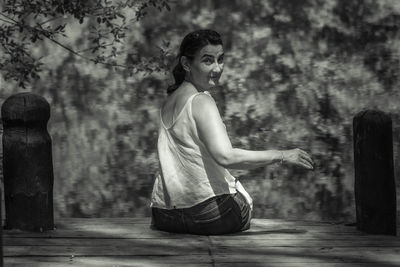 Rear view portrait of woman sitting by lake