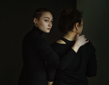 Young couple looking away while standing against black background
