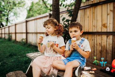 Preschool age kids sitting on picnic table eating ice cream cones