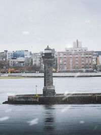 Buildings by sea against sky in city during winter