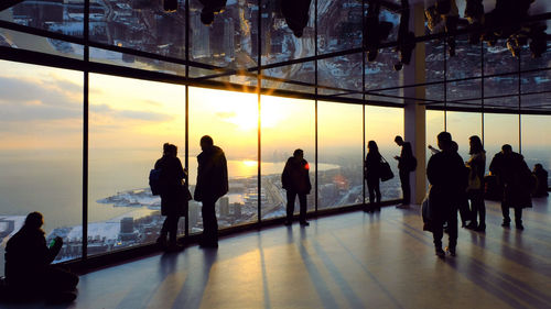 Silhouette people waiting at modern building during sunset