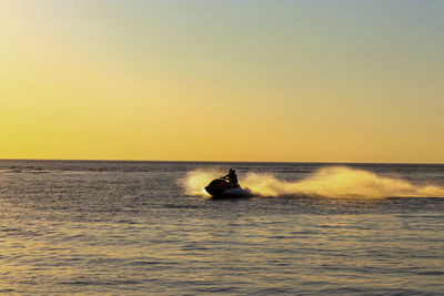 Silhouette boat in sea against clear sky during sunset