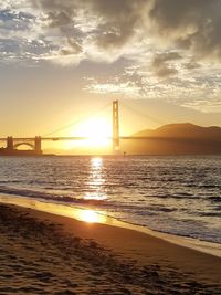 Suspension bridge over sea during sunset