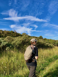 Rear view of man standing on field against sky