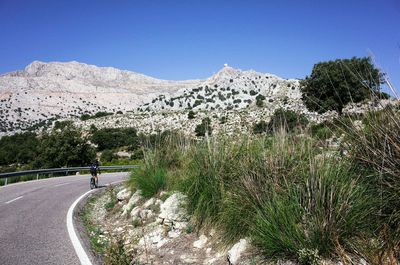 Road by mountains against clear blue sky