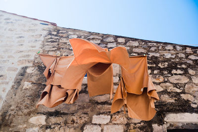 Low angle view of clothes hanging on clothesline against stone wall