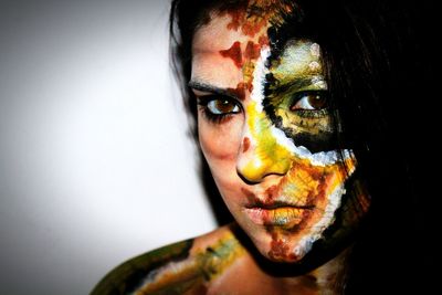 Portrait of young woman with face paint against wall