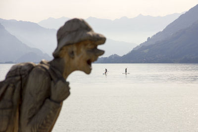 Horse in sea by mountains against sky