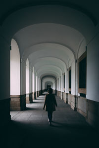 Rear view of man walking in corridor of building